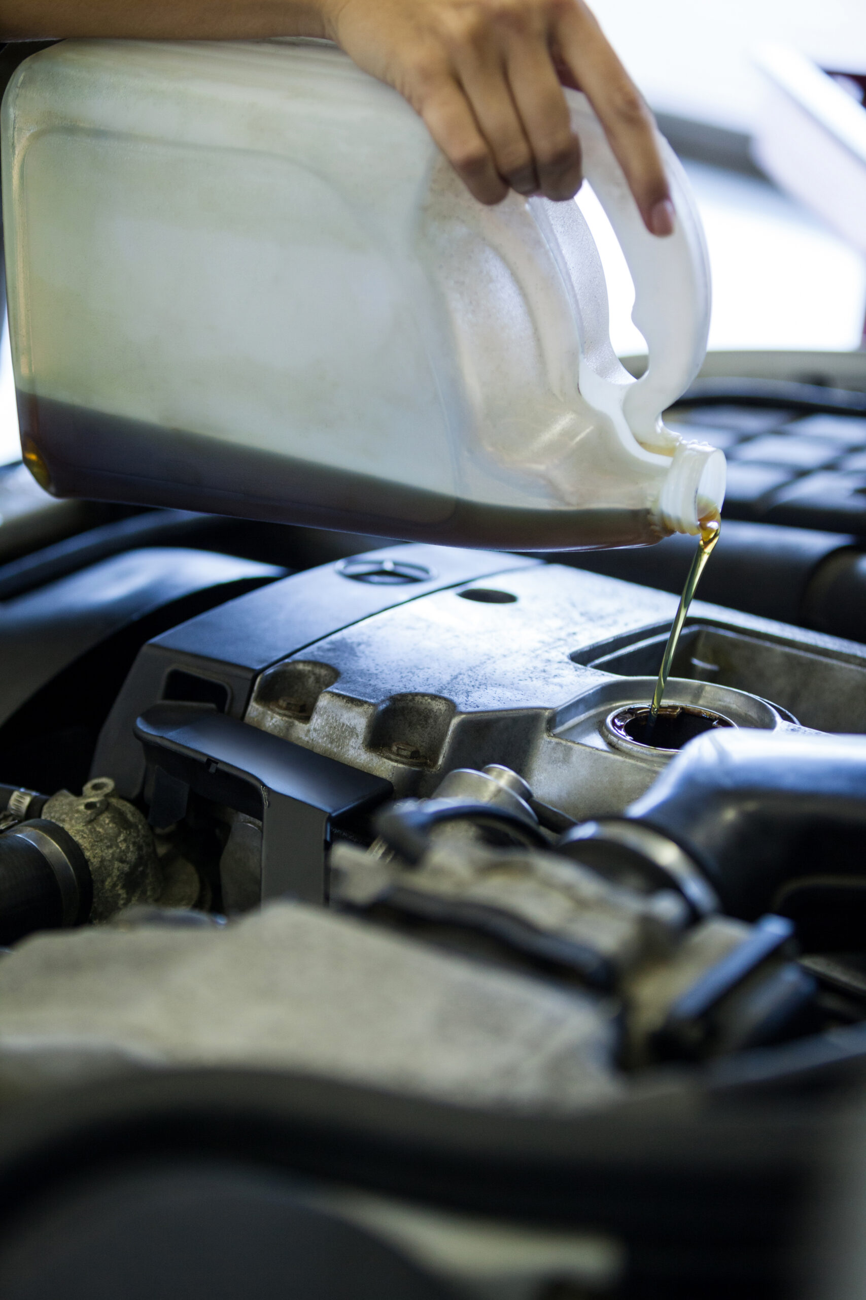 Mechanic pouring oil lubricant into the car engine Mechanic pouring oil lubricant into the car engine