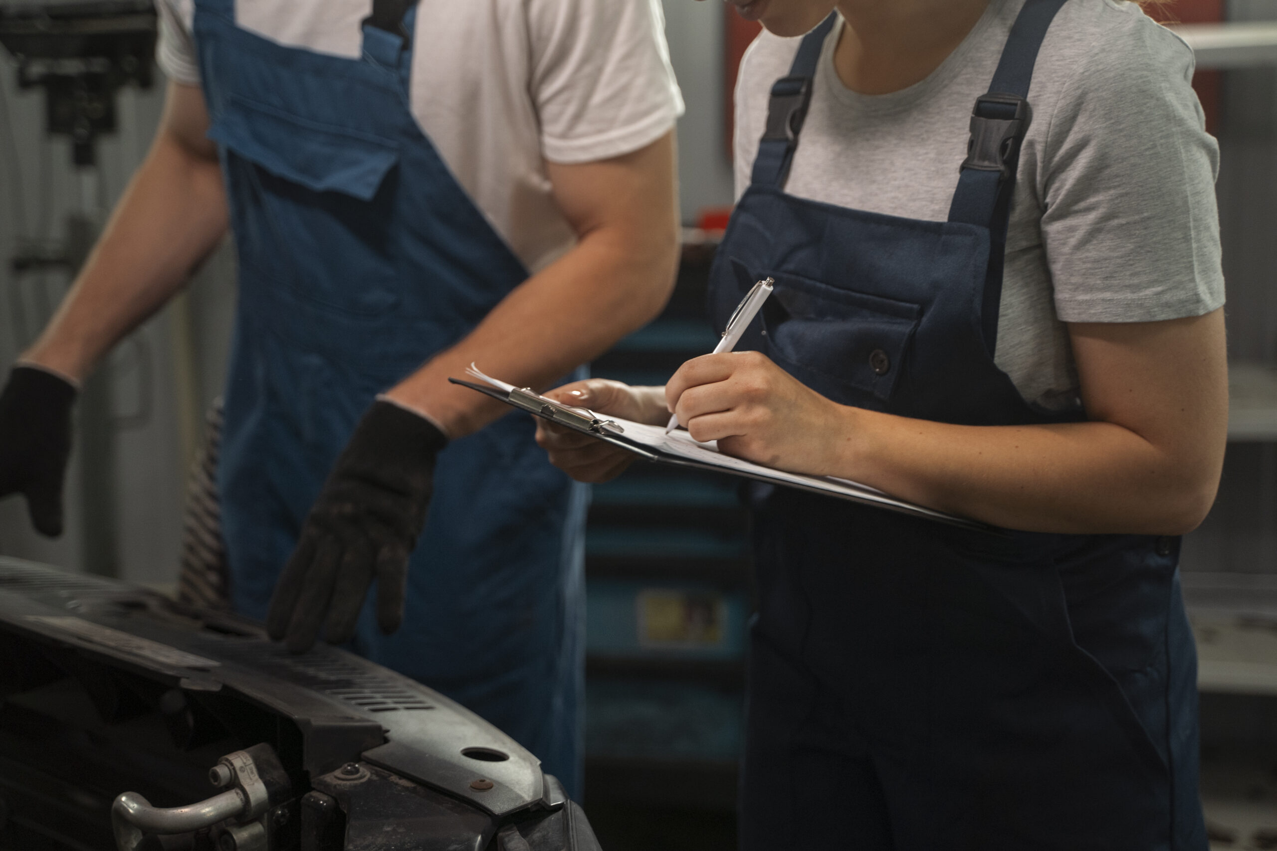 mecanicos-masculinos-y-femeninos-que-trabajan-en-la-tienda-de-un-automovil Mecanicos masculinos y femeninos que trabajan en la tienda de un automovil